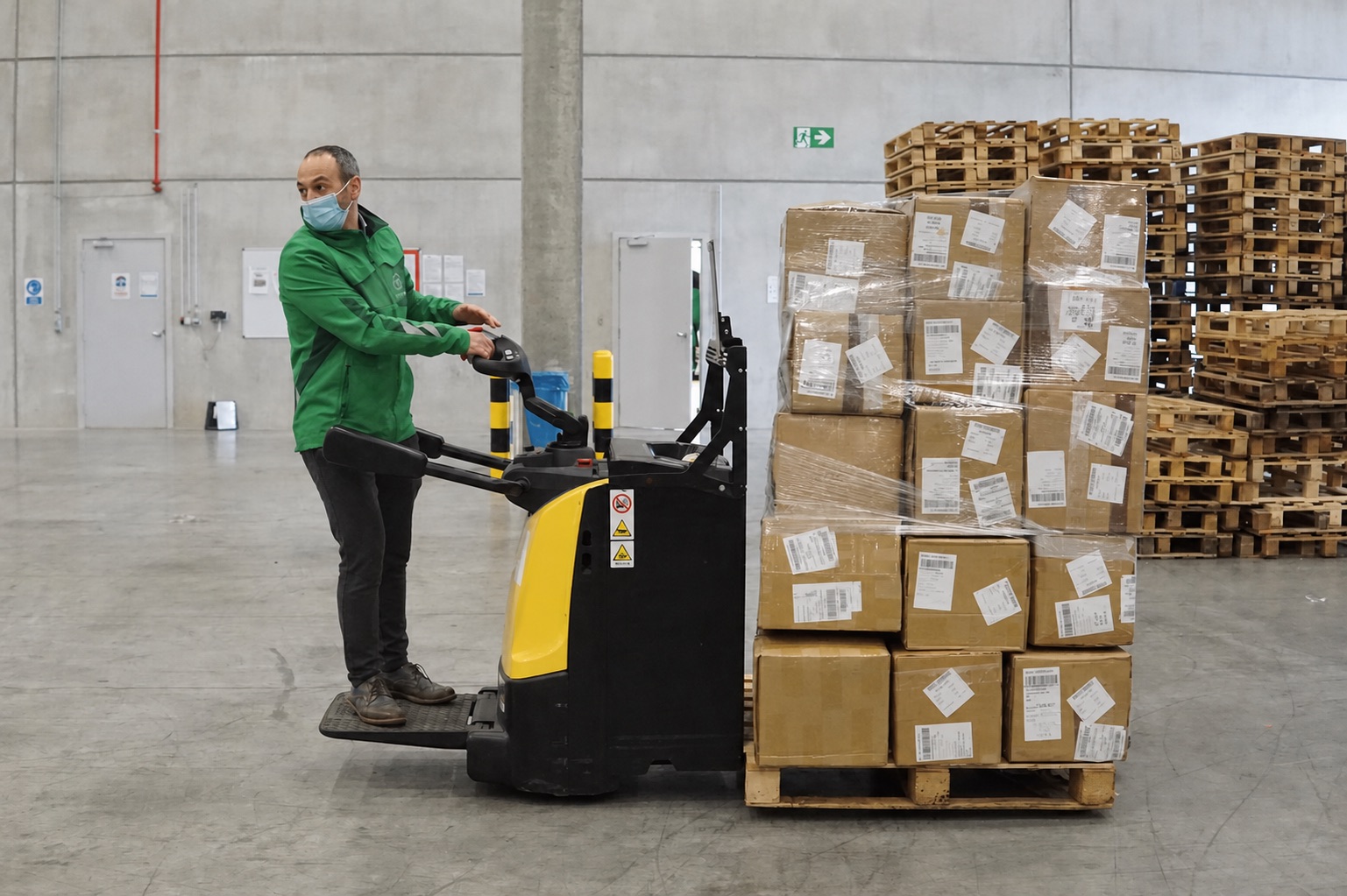 Warehouse operator moving prepared ecommerce parcels on a pallet.